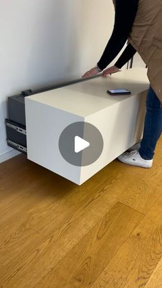 a person standing next to a white box on top of a wooden floor