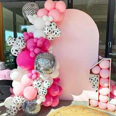 a table topped with lots of pink and white balloons next to a giant heart shaped cake