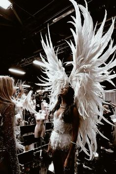 two women dressed in white feathers standing next to each other