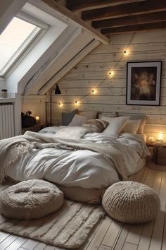 an attic bedroom with white walls and wood flooring is lit by warm lighting from the windows