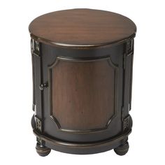 a round wooden table sitting on top of a white floor next to a black and brown cabinet