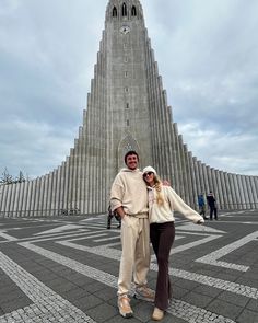 two people standing in front of a very tall building