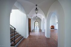 an arched hallway with red tile flooring and white walls