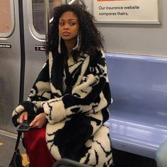 a woman is sitting on a train with her luggage and looking off into the distance