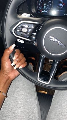 a woman holding a cell phone in her hand while sitting in the driver's seat of a car