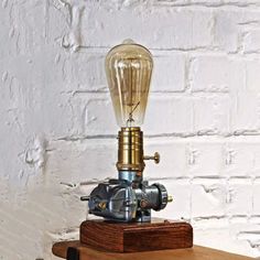 a light bulb sitting on top of a wooden table next to a white brick wall