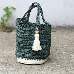 a green crocheted bag with a tassel hanging from it's side