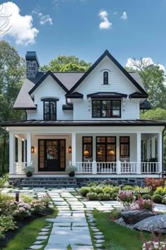 a white house with black trim and lots of windows on the front porch, along with stone steps leading up to it