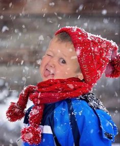 a young boy wearing a red hat and scarf in the snow with his mouth open