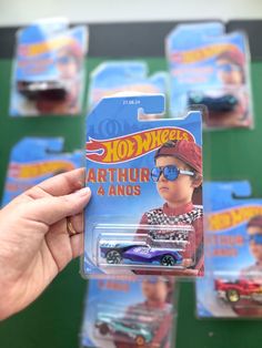 a hand holding a hot wheels car in front of some other cars on display at a toy store