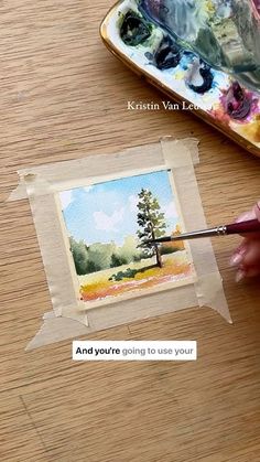 someone is painting an image with watercolors on paper and then using a brush