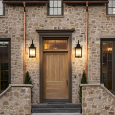 a stone house with two lights on the front door