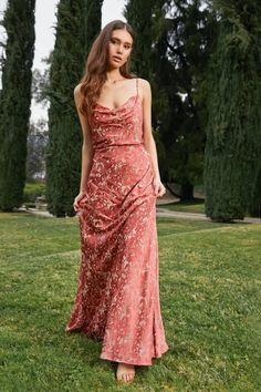 a woman standing in the grass wearing a red dress