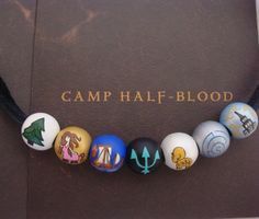 a bracelet with different colored beads on it and a book that says camp half - blood