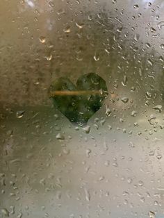 a heart shaped object sitting on top of a window covered in raindrops,