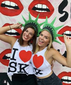 two young women standing next to each other in front of a wall with the statue of liberty on it