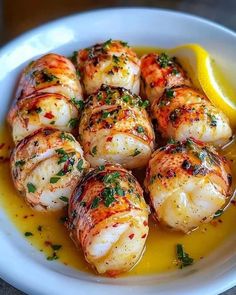 a white bowl filled with cooked shrimp and lemon wedges