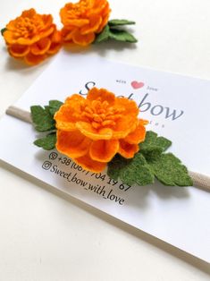 two orange flowers on top of a white card