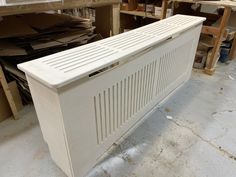 a large white radiator sitting on top of a floor next to wooden shelves