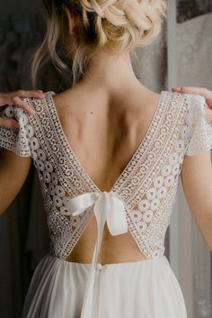 the back of a woman's wedding dress with a white bow on her shoulder