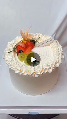 a white cake topped with fruit on top of a table