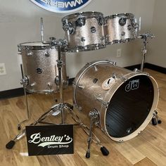 a silver drum set sitting on top of a hard wood floor next to a sign