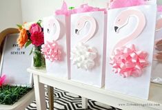 pink and white flamingo bags with bows on them sitting on top of a table