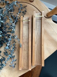 two pieces of wood sitting on top of a wooden table next to flowers and scissors