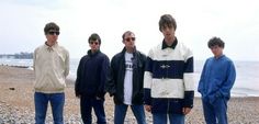 four young men standing next to each other on a beach