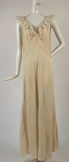 ANTIQUE 1930’S SOFTEST SILK LONG IVORY DRESS W RUFFLED NECKLINE  DATING TO THE 1930’S FASHIONED OF AN OFF WHITE IVORY SOFT SILK CREPE AND THERE ARE NO CLOSURES, MUST BE SLIPPED OVER THE HEAD TO BE WORN. THE V SHAPED NECKLINE IS TRIMMED IN MACHINE EMBROIDERED NYLON ORGANZA RUFFLES WITH A FLORAL PATTERN AND A SATIN RIBBON ENCIRCLING THE NECKLINE TO TIE CLOSED IN THE FRONT.   CONDITION:  TWO PINHEAD HOLES SEEN WHEN THE SKIRT IS HELD TO THE LIGHT WITH SIX VERY FAINT BROWN PINHEAD STAI Long Ivory Dress, Vintage Satin Dress, 1930s Fashion Women, Vintage 1930s Dress, Vintage Slip Dress, Long Slip Dress, 1930s Dress, Ivory Dress, Ruffled Neckline