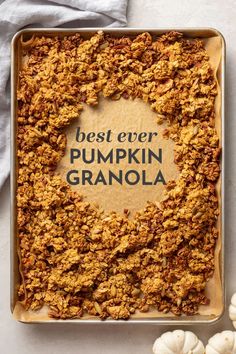 the best ever pumpkin granola recipe in a baking pan on a white surface with mini pumpkins around it