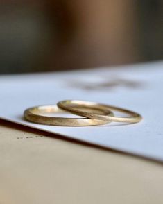 two gold wedding rings sitting on top of a piece of paper next to each other