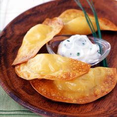 some food is on a wooden plate with green onions and sour cream in the middle