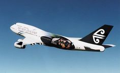 an air new zealand plane flying in the sky with people on it's side