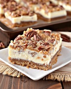 a piece of pecan pie on a plate next to a tray of pecans