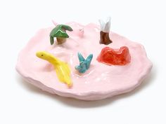 small toy figurines sitting on top of a pink plate