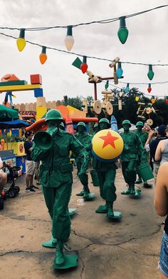 some people in green uniforms are walking down the street with balloons and decorations around them