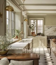 an elegant kitchen with marble counter tops and white cabinets, along with potted plants