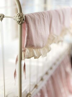 a baby crib with a pink blanket on it's side and a metal rail