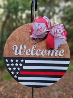 a welcome sign hanging from the side of a wooden sign with red, white and blue ribbon