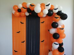 an orange and black balloon arch decorated with bats