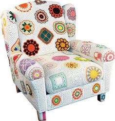 an upholstered chair with colorful crocheted flowers on the back and arms