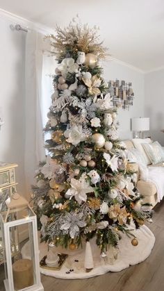 a white christmas tree with gold and silver ornaments in a living room decorated for the holidays