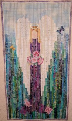 a quilted wall hanging with an angel in the middle and flowers on it's side