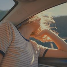 a woman sitting in the back seat of a car with her hand on her head