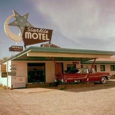 an old motel with a red car parked in front and a large star on the sign