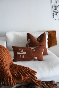 three decorative pillows on a white couch in a living room with an orange throw pillow