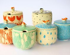 four ceramic containers with birds on them sitting next to each other in front of a white background