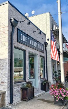 one twenty man storefront with american flag in the window and potted plants outside