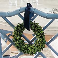 a wreath is hanging on the back of a chair with blue ribbon and silverware